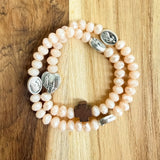 Pulsera rosario elástica en cristal de murano beige talla S con dijes de santos en zamak y cruz de madera vista en detalle - VII Sacramentos