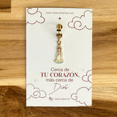 Dije de la Virgen de Fátima con argolla dorada de 12mm sobre tarjeta con mensaje religioso