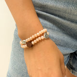 Pulsera rosario elástica en cristal de murano beige talla S con dijes de santos en zamak y cruz de madera vista en detalle - VII Sacramentos