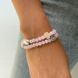 Pulsera rosario elástica de murano rosado talla S en muñeca delgada, mostrando el diseño de doble vuelta y cruz de madera.