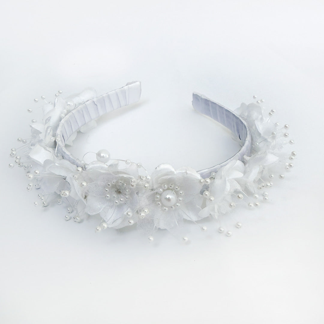 Primer plano de los detalles de flores textiles blancas y perlas de bisutería del tocado de comunión - VII Sacramentos