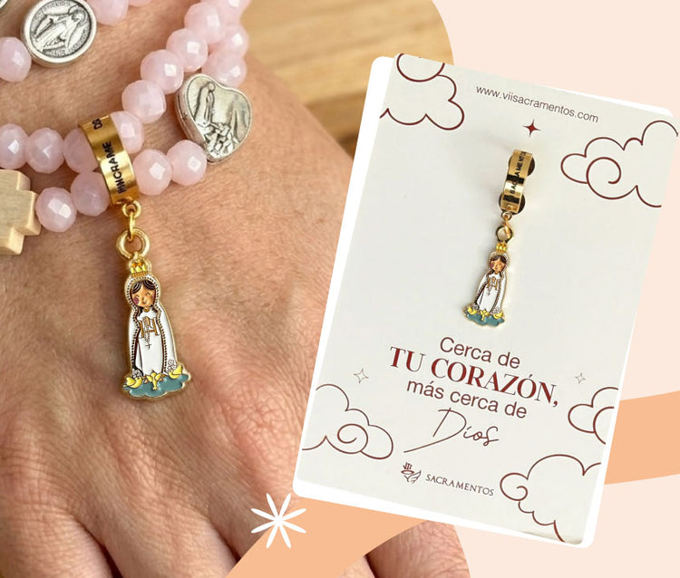 Charm o dije de la Virgen de Fátima en oro y esmalte blanco sobre empaque de la marca Sacramentos.